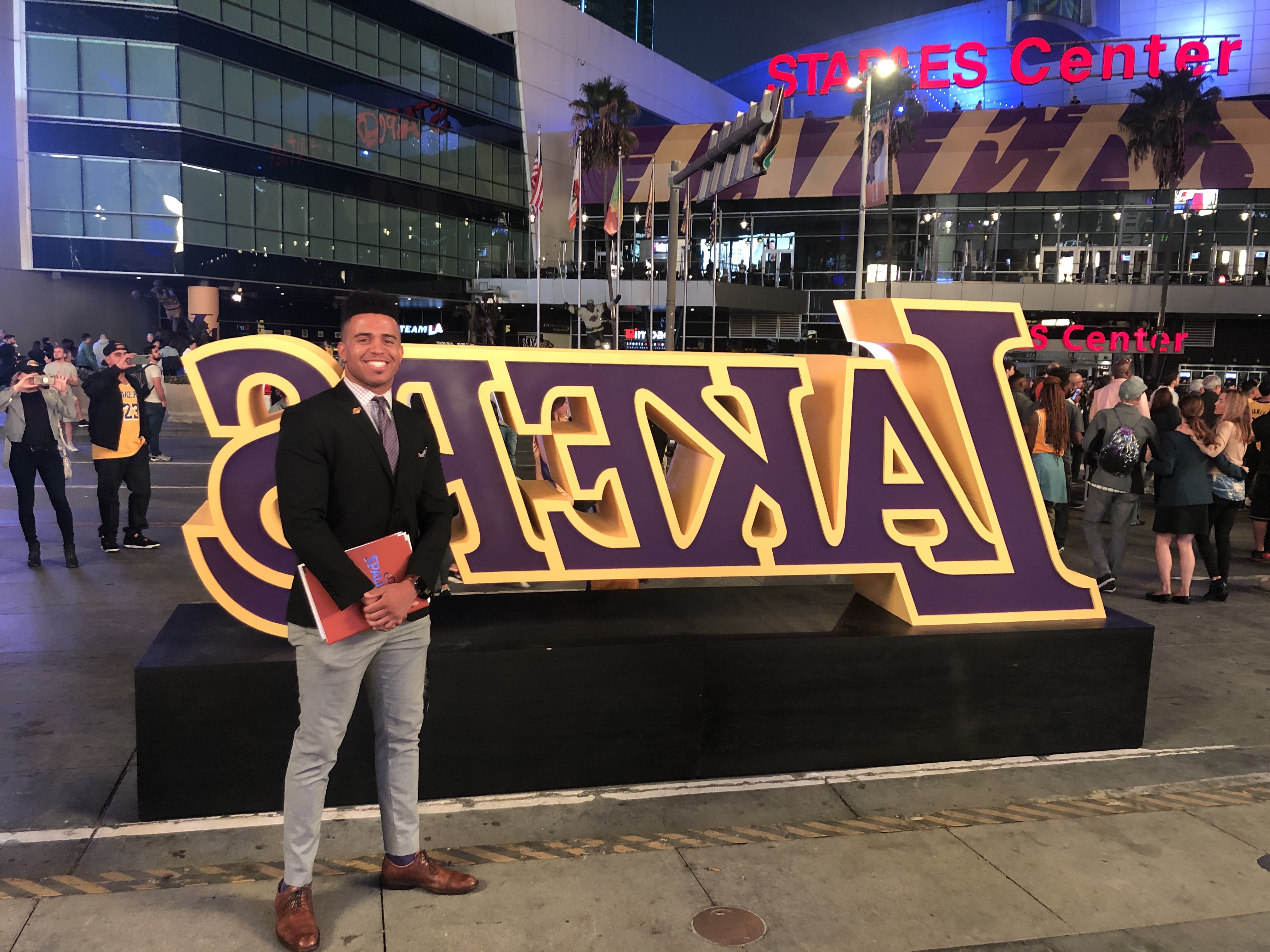 Myles McKee Osibodu stands in front of the L.A. Lakers sign at the Staples Center.