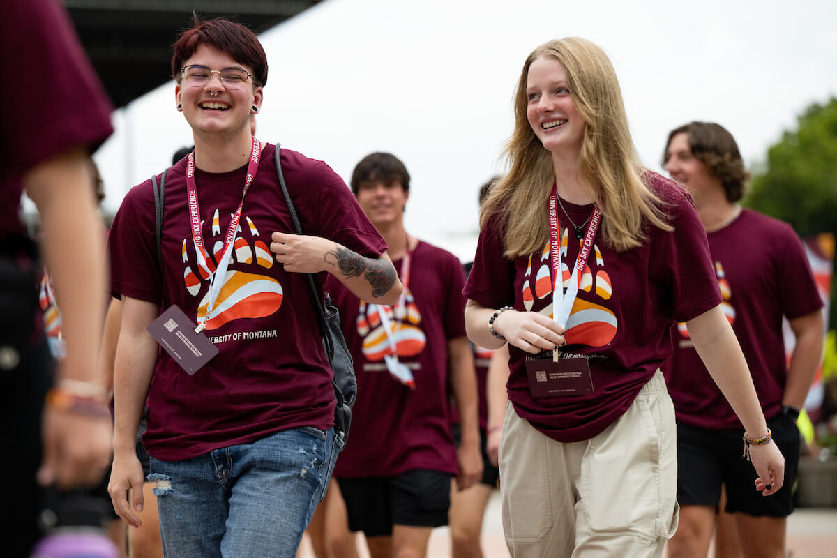 two students in griz colored clothes walking with a group of other students